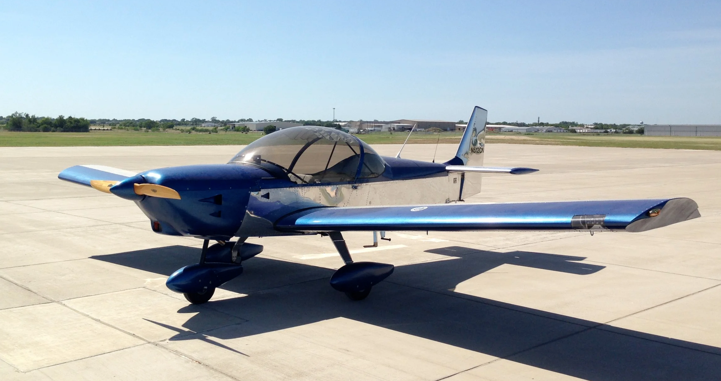 Blue-and-silver single-engine light aircraft parked on an airport runway apron