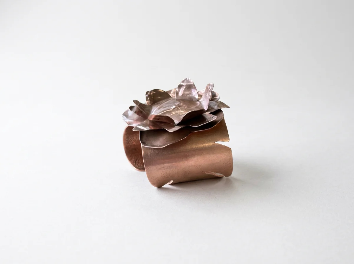 Handcrafted copper flower cuff bracelet on a white background