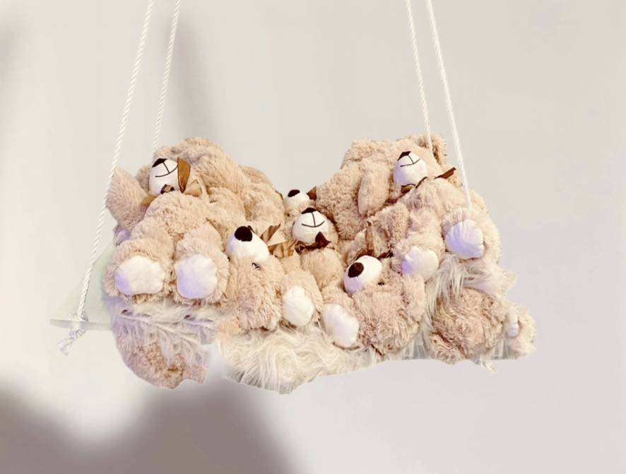Cluster of beige teddy bear plush toys hanging in a suspended fabric swing