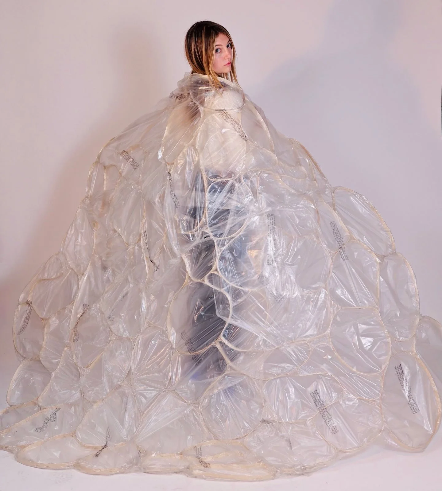 Woman wearing an oversized avant-garde dress made from transparent plastic bags