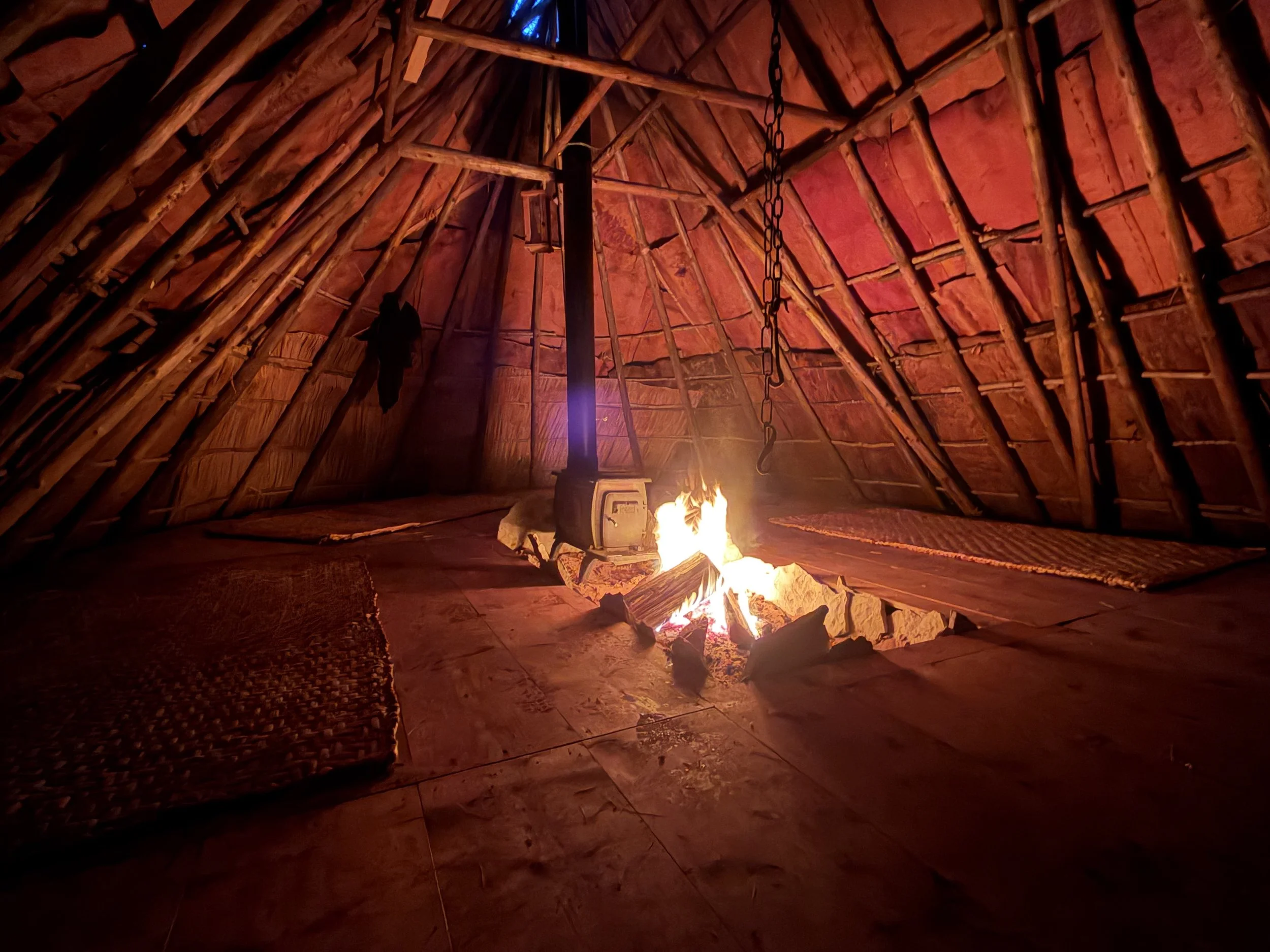 Warm firelight illuminating the bark walls inside Birch House