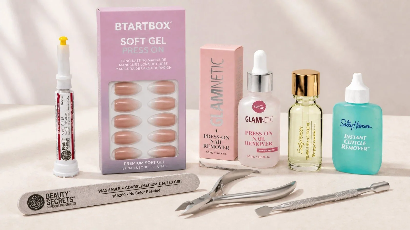 Mandi's press-on nail prep kit: Beauty Secrets nail glue and file, BTArtbox press-ons, Glamnetic remover serum, Sally Hansen cuticle oil and cuticle remover, and a cuticle nipper and pusher