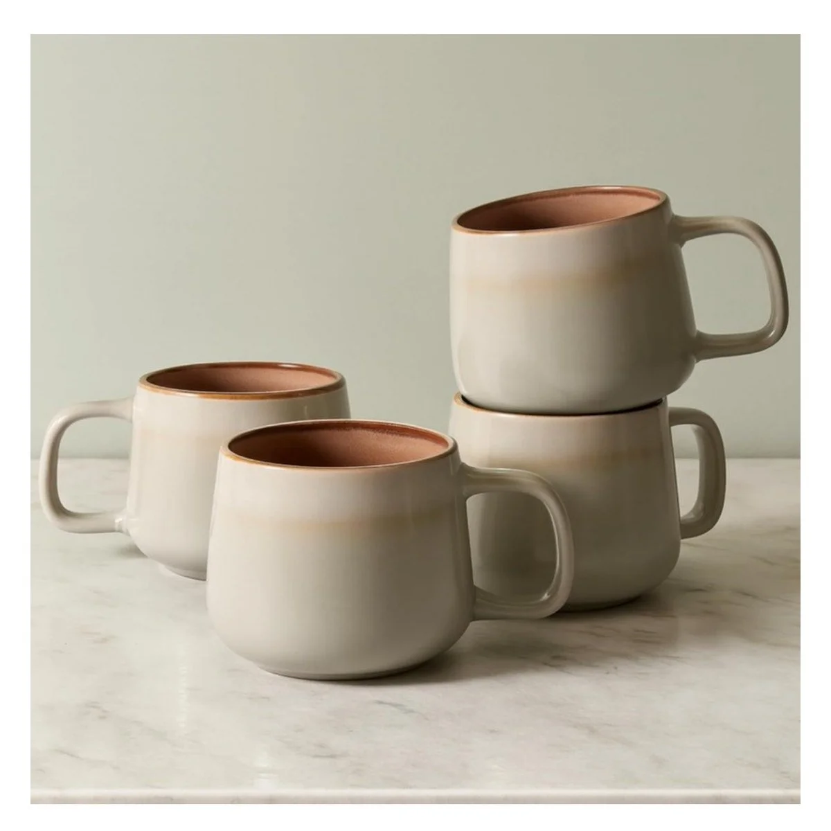 Four Ava Nord sage stoneware mugs on a marble counter