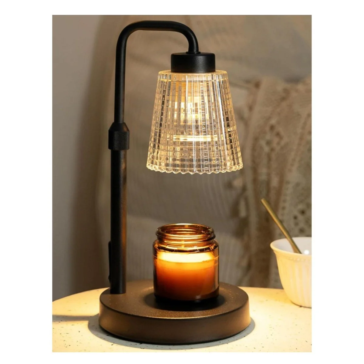 Candle warmer lamp with a glowing jar candle on a side table