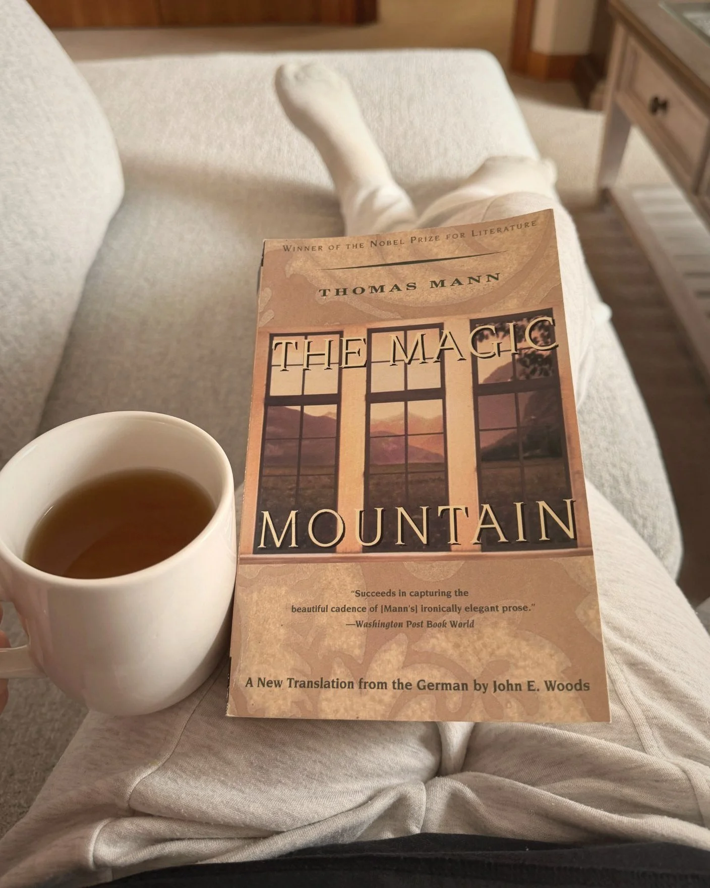 The Magic Mountain by Thomas Mann with a cup of tea on a cozy sofa