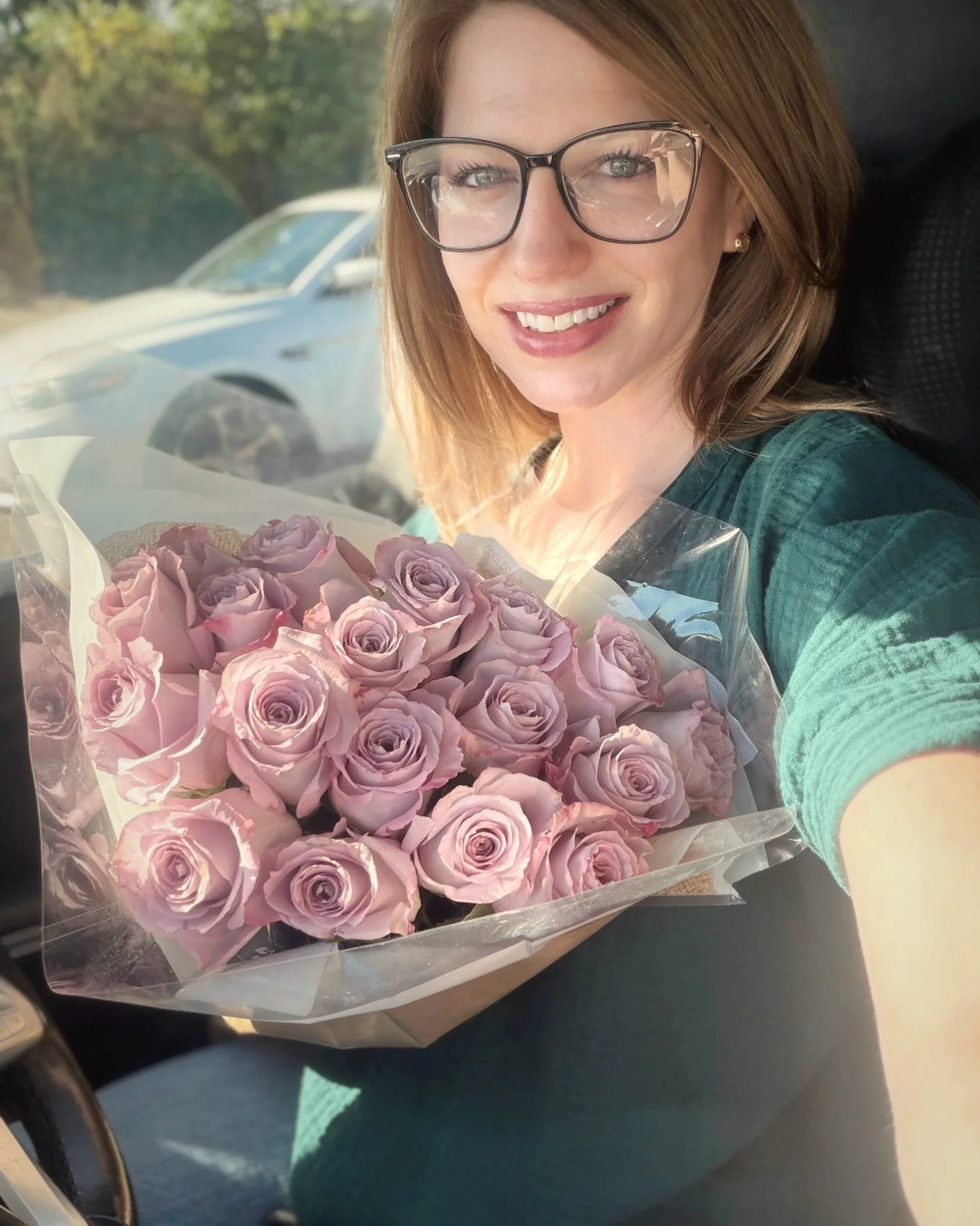 Mandi Lyne smiling with a bouquet of lavender roses