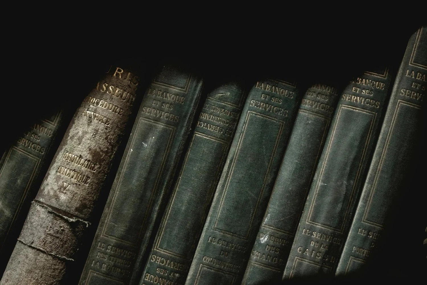 Row of dark vintage hardcover books in moody light