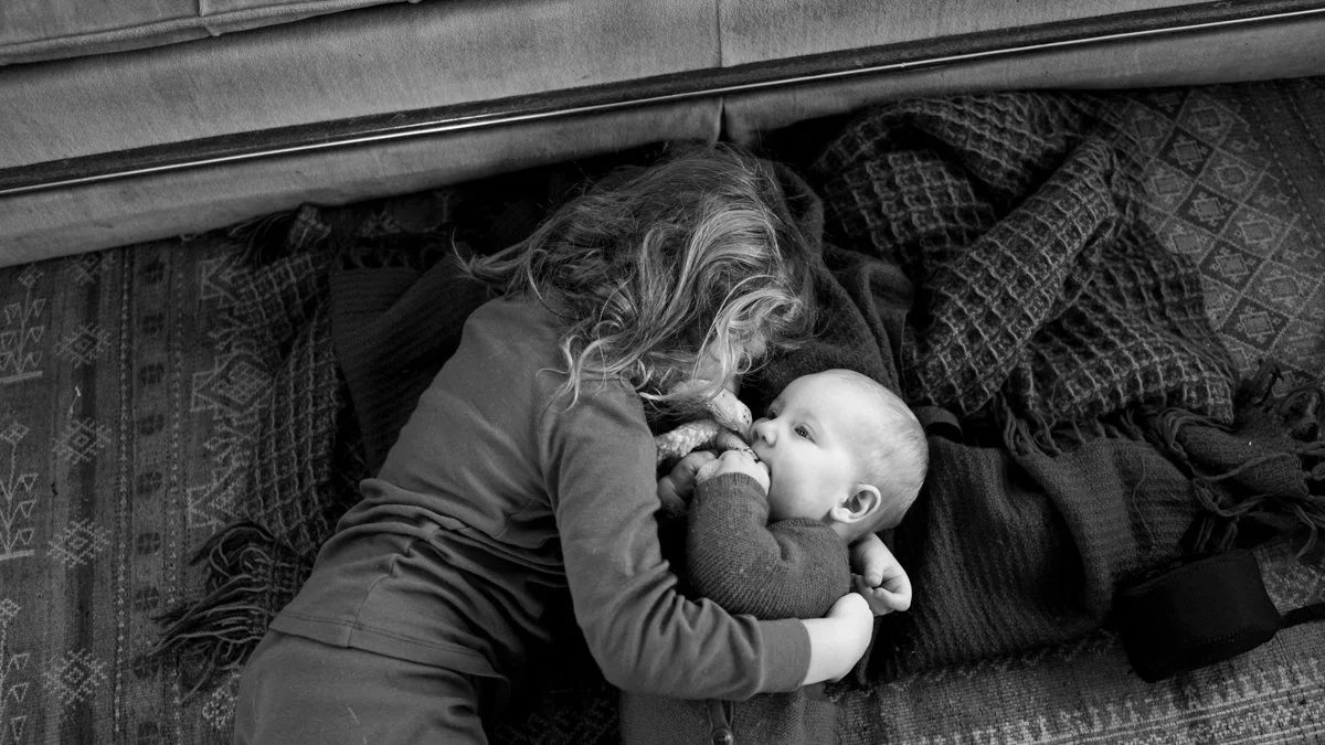older brother greets his baby sister in a tender hug