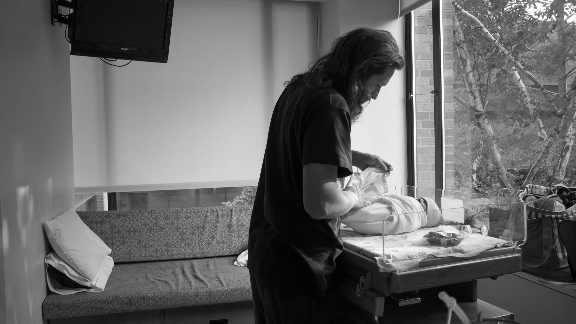 New father caring for a newborn baby in a hospital bassinet