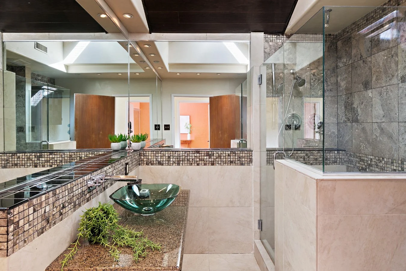 Luxury bathroom with glass-enclosed walk-in shower, vessel sink, granite countertops, mosaic tile accents, and large mirrors
