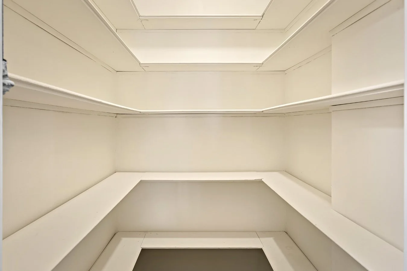 Upward view of an empty white architectural interior with layered molding and recessed ceiling details