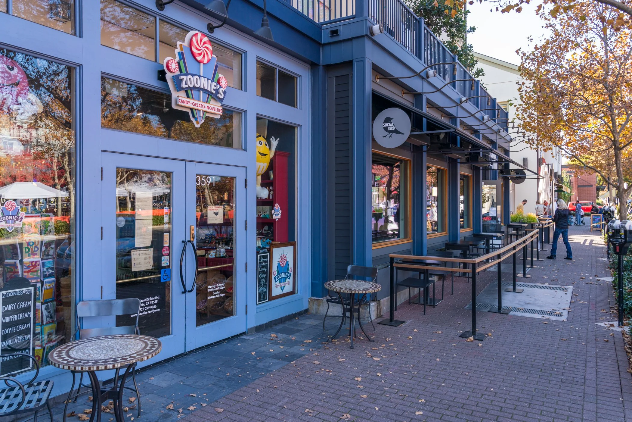 Zoonie's candy and gelato shop storefront with outdoor seating on a tree-lined brick-paved sidewalk