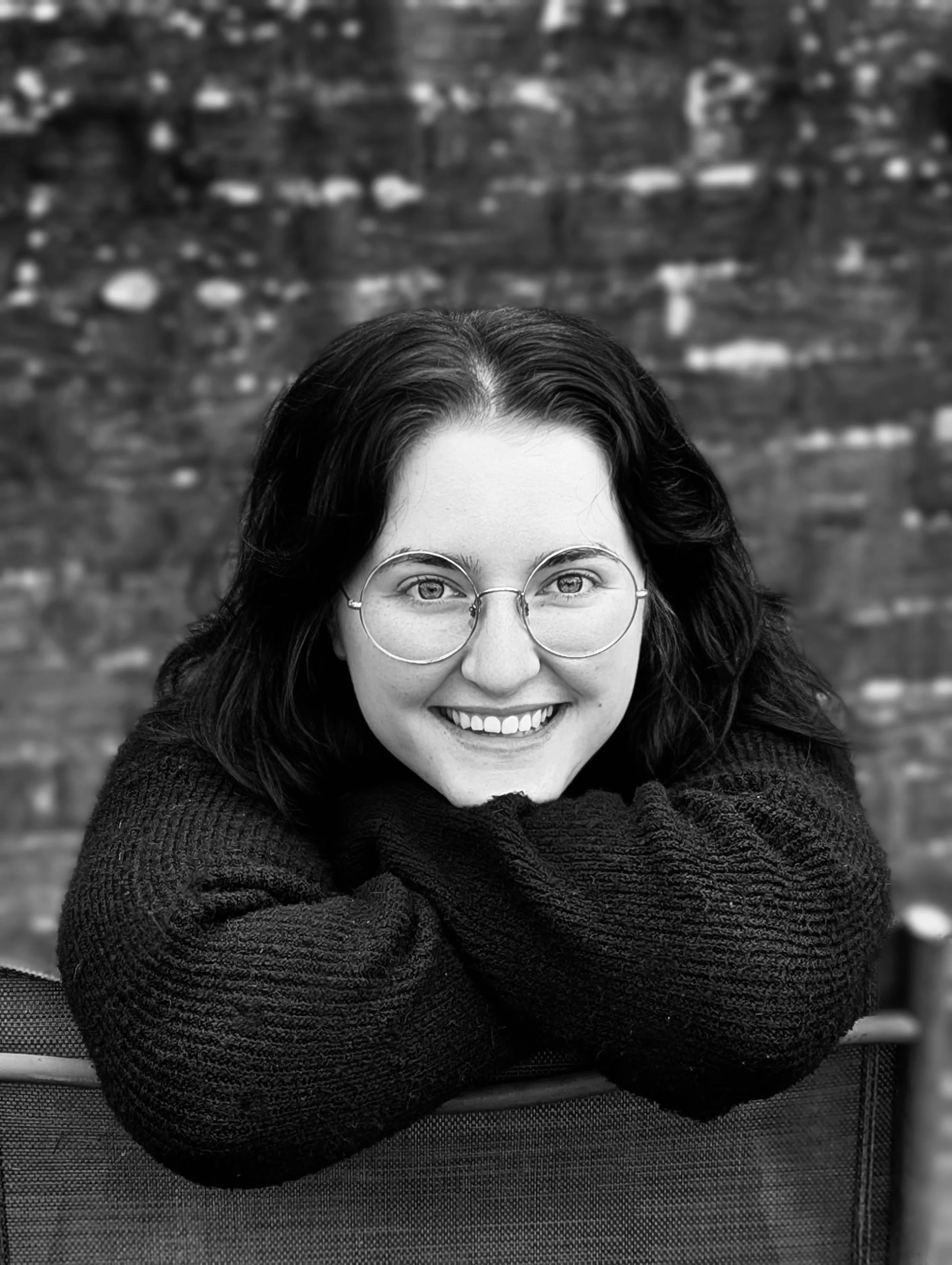 A Headshot of Dana Kelly the author - a woman in her 20’s with black hair, pale skin and round glasses.