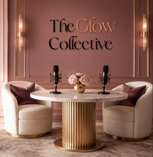 Elegant podcast studio with two microphones, round marble table, pink flowers, modern lounge chairs, and “The Glow Collective” wall lettering