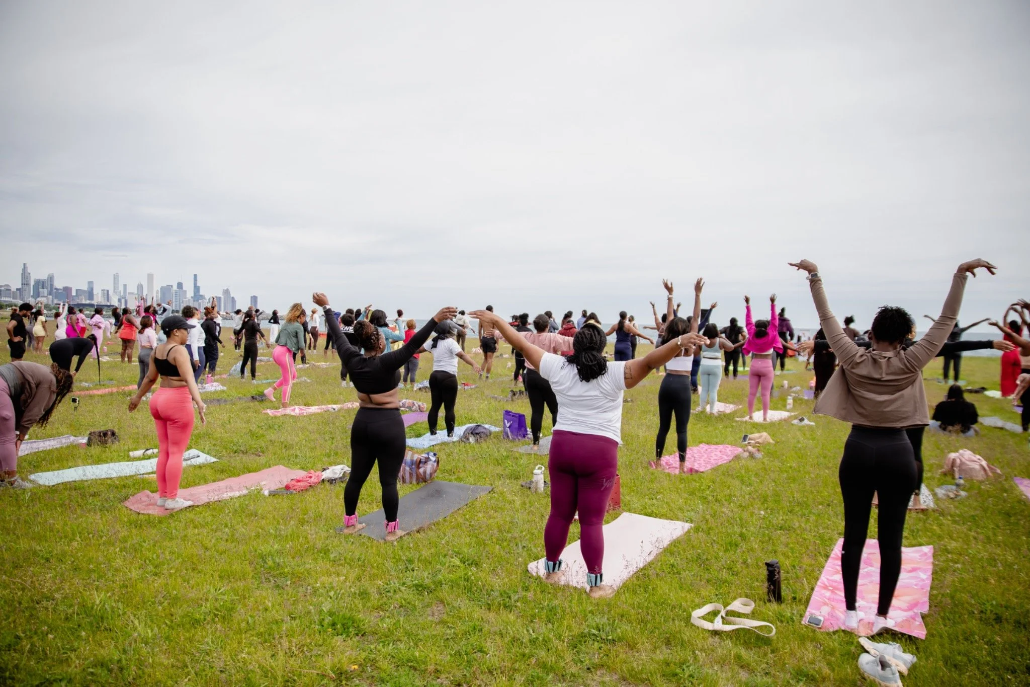 Community members moving together in an outdoor Pilates class beside Lake Michigan.