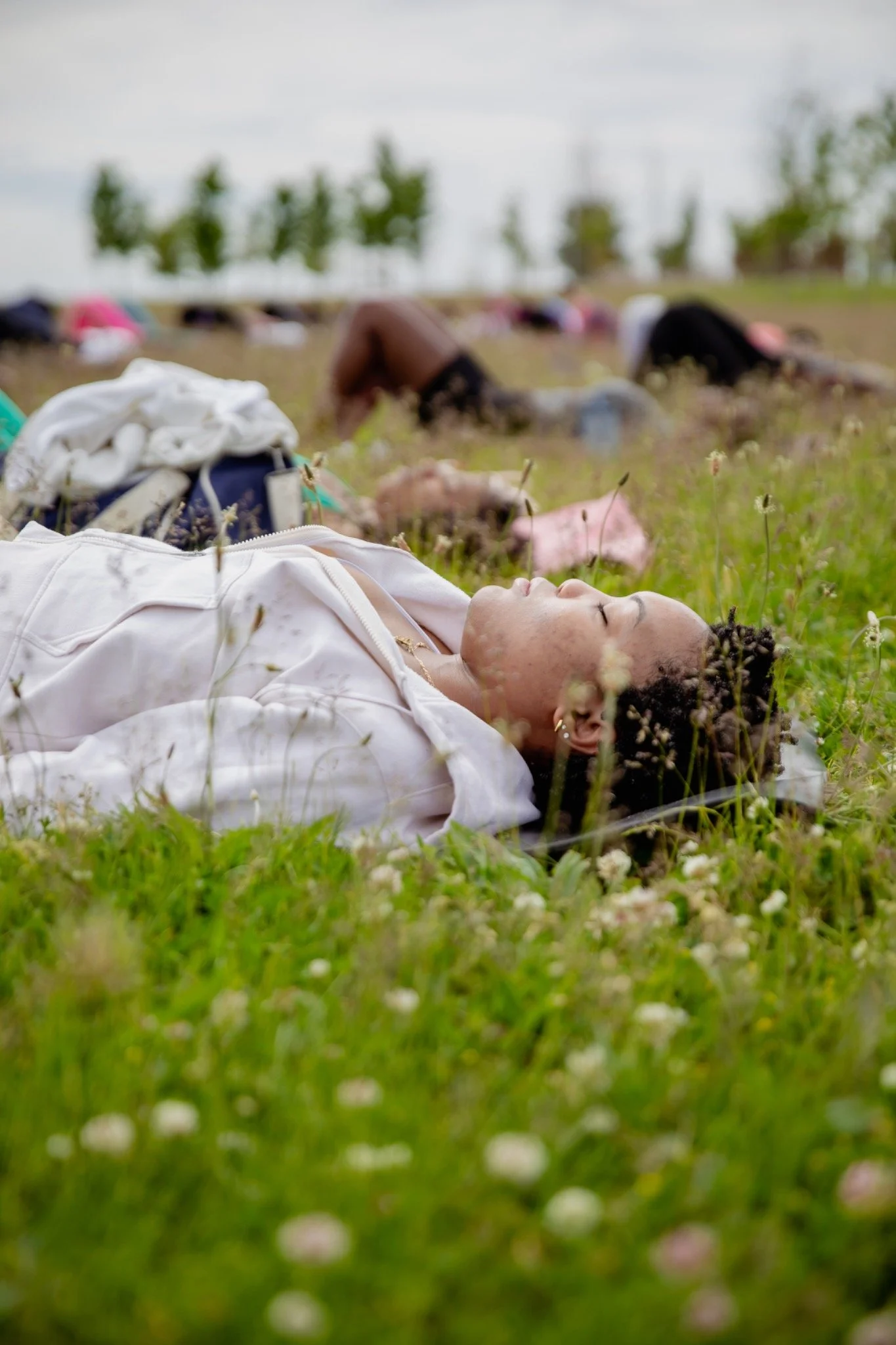 Participant resting on a mat during an outdoor community Pilates class beside Lake Michigan.