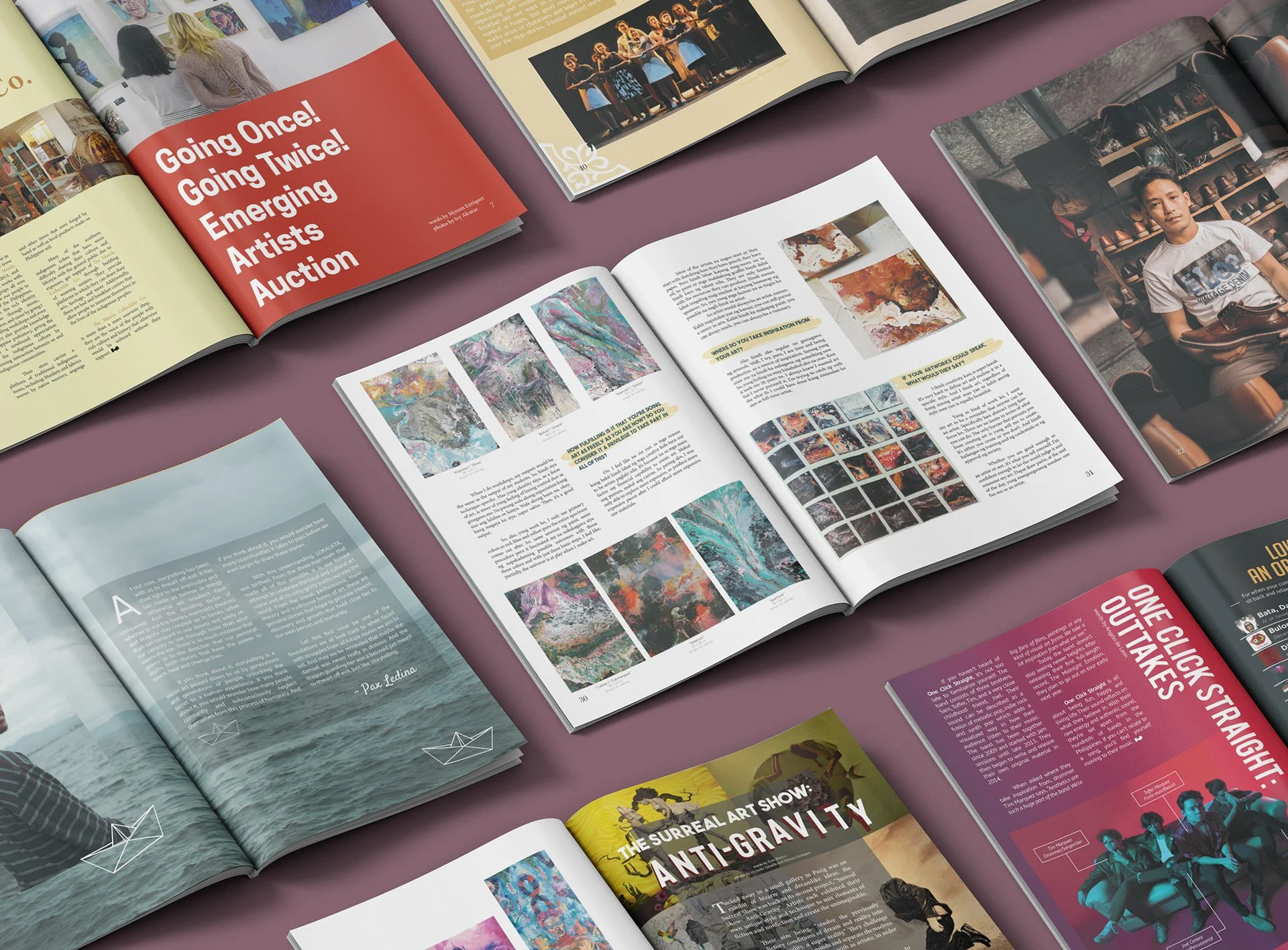 Overhead view of open art and culture magazines arranged on a mauve surface, featuring paintings, artist profiles, exhibitions, and a portrait of an artist.