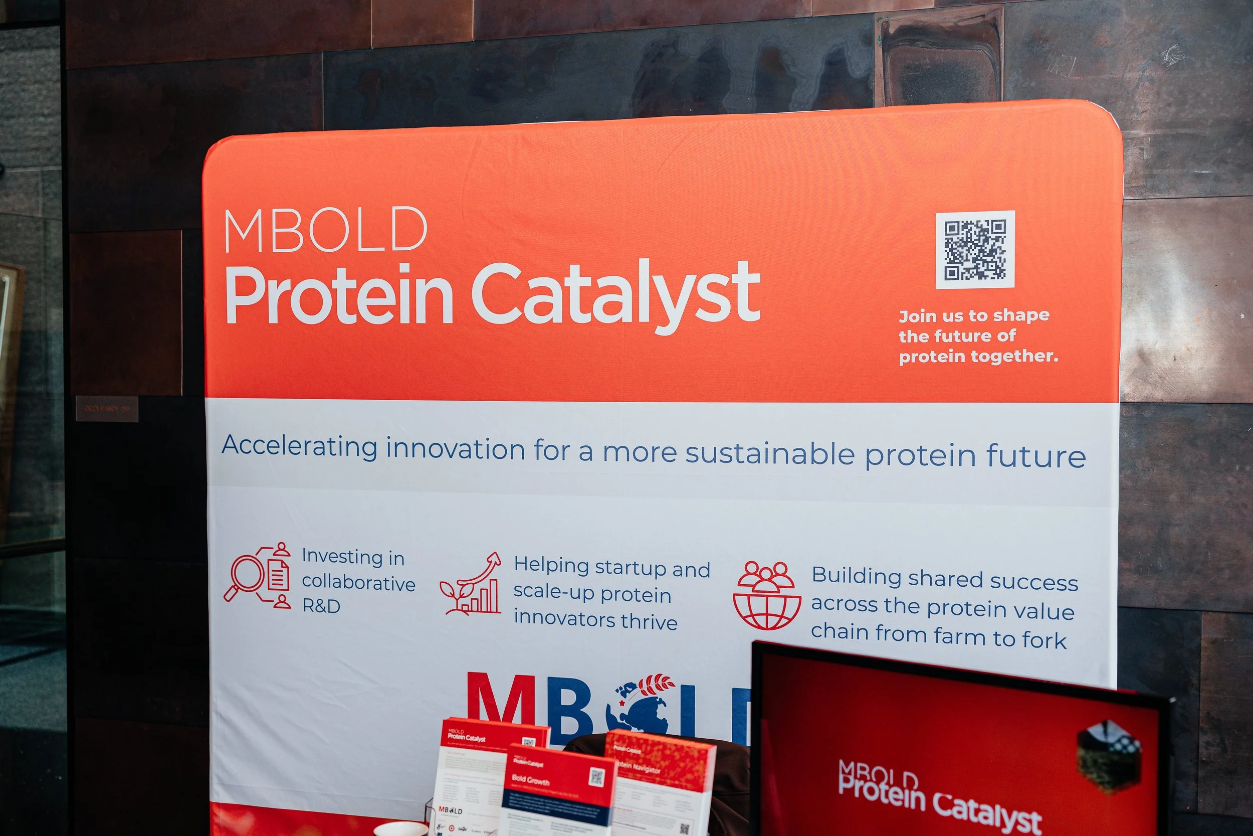 MBOLD Protein Catalyst promotional display featuring a QR code and messaging about sustainable protein innovation