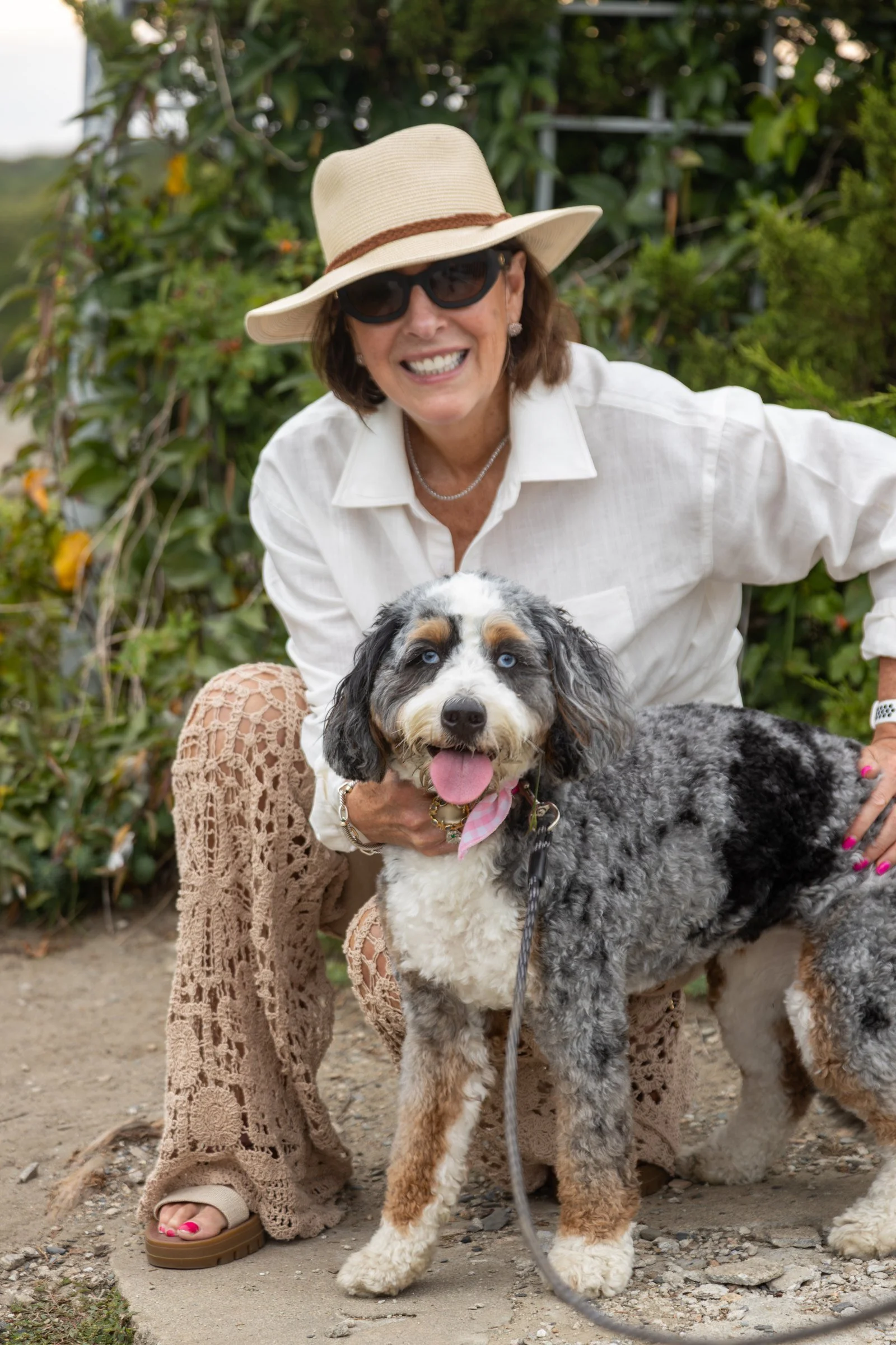 Lisa smiling with her Mini Bernedoodle Gracie in a garden