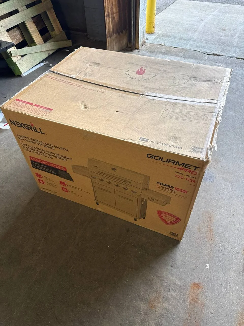 Nexgrill Gourmet Pro 6-burner stainless steel propane gas grill in its original cardboard box, second angle showing the box side