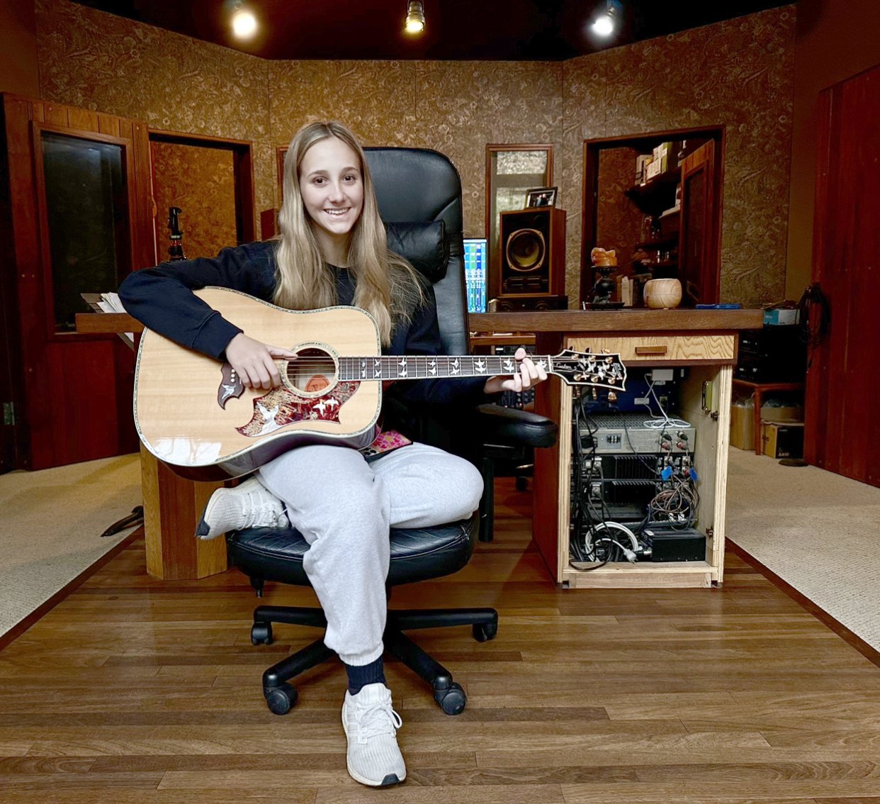 Young woman playing an acoustic guitar in a recording studio