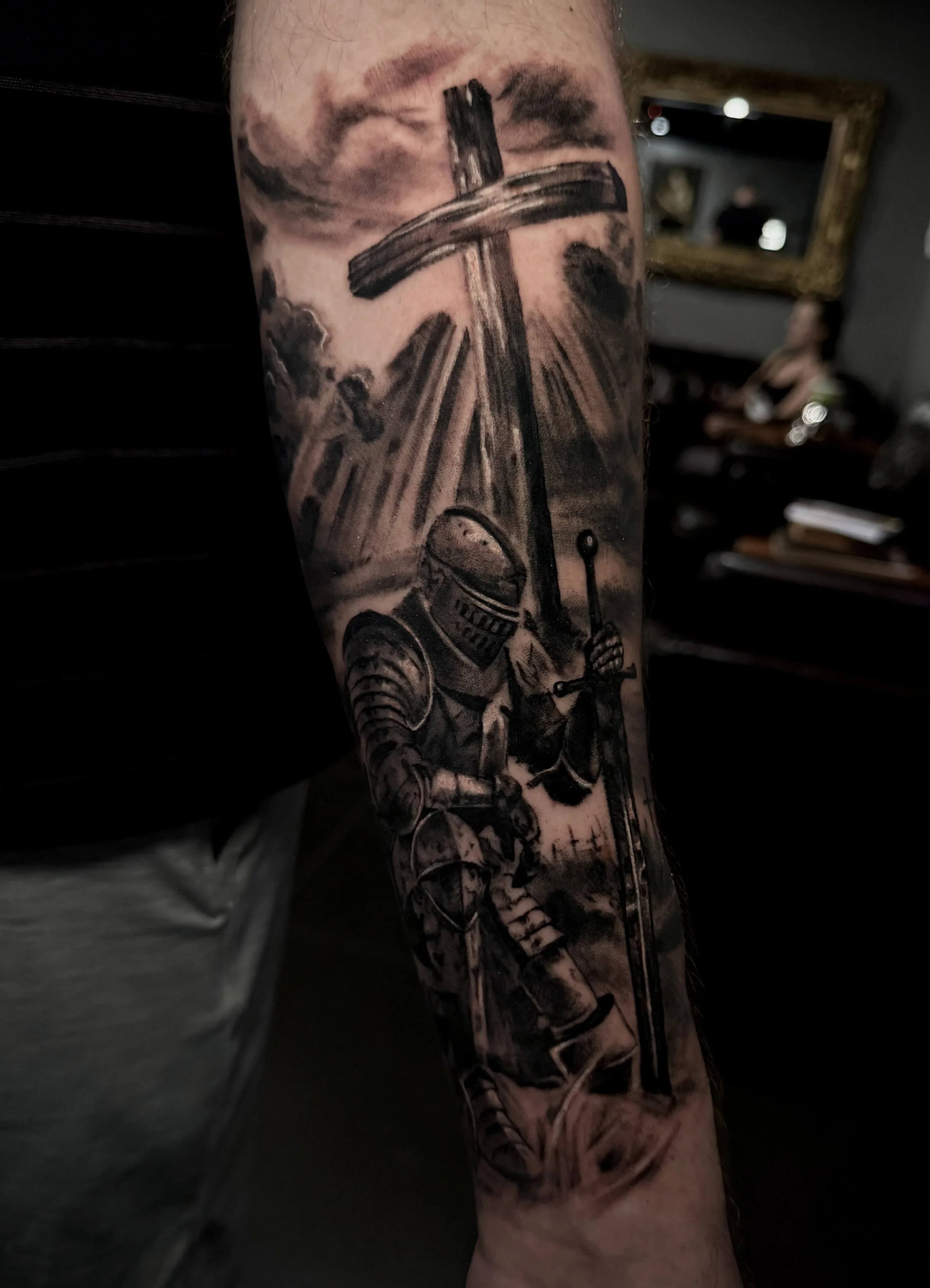 Close-up of a heavily tattooed forearm featuring a detailed black-and-gray skeleton and skull design.