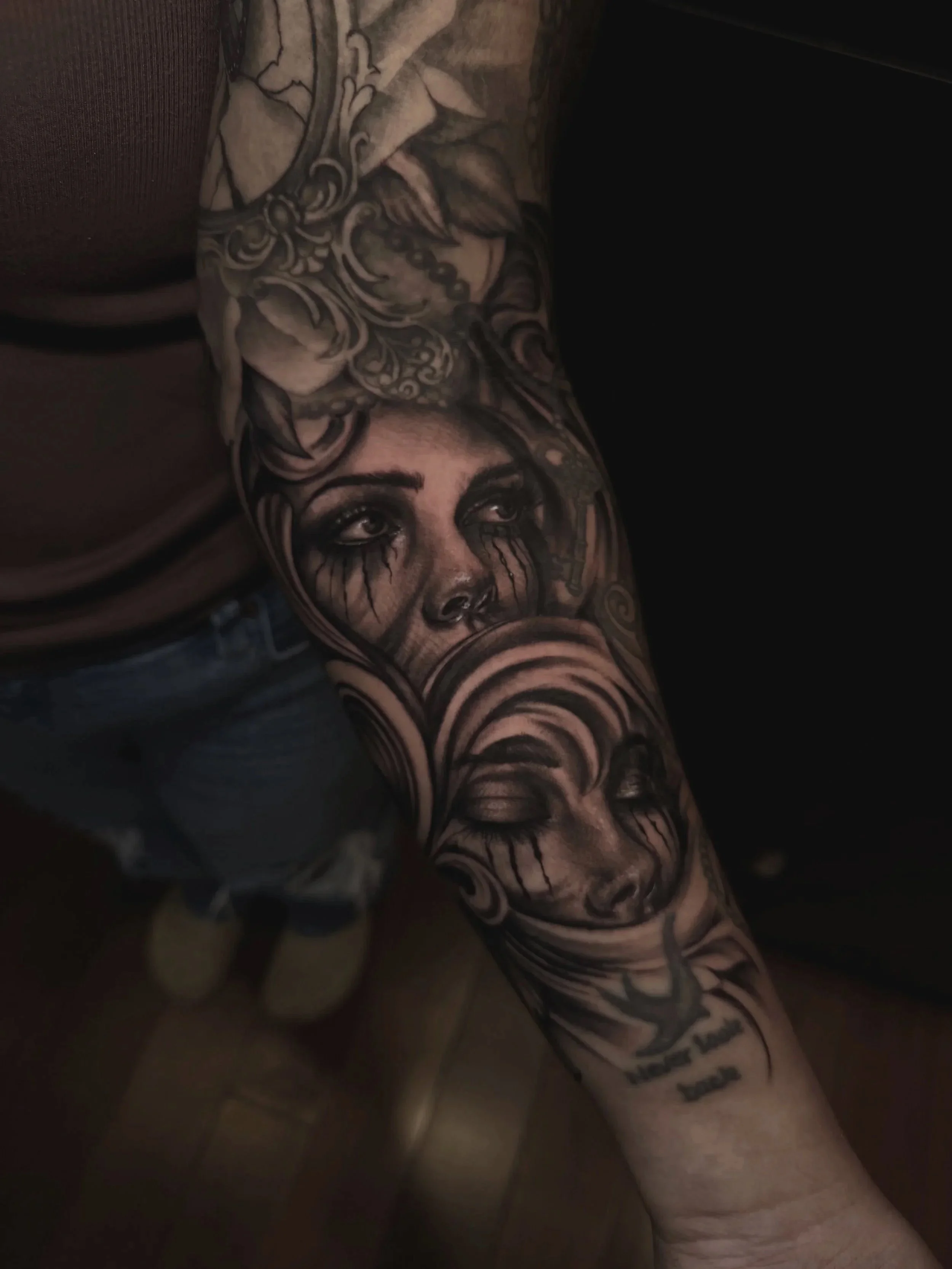 Close-up of an ornate floral tattoo covering a person’s shoulder and upper arm.