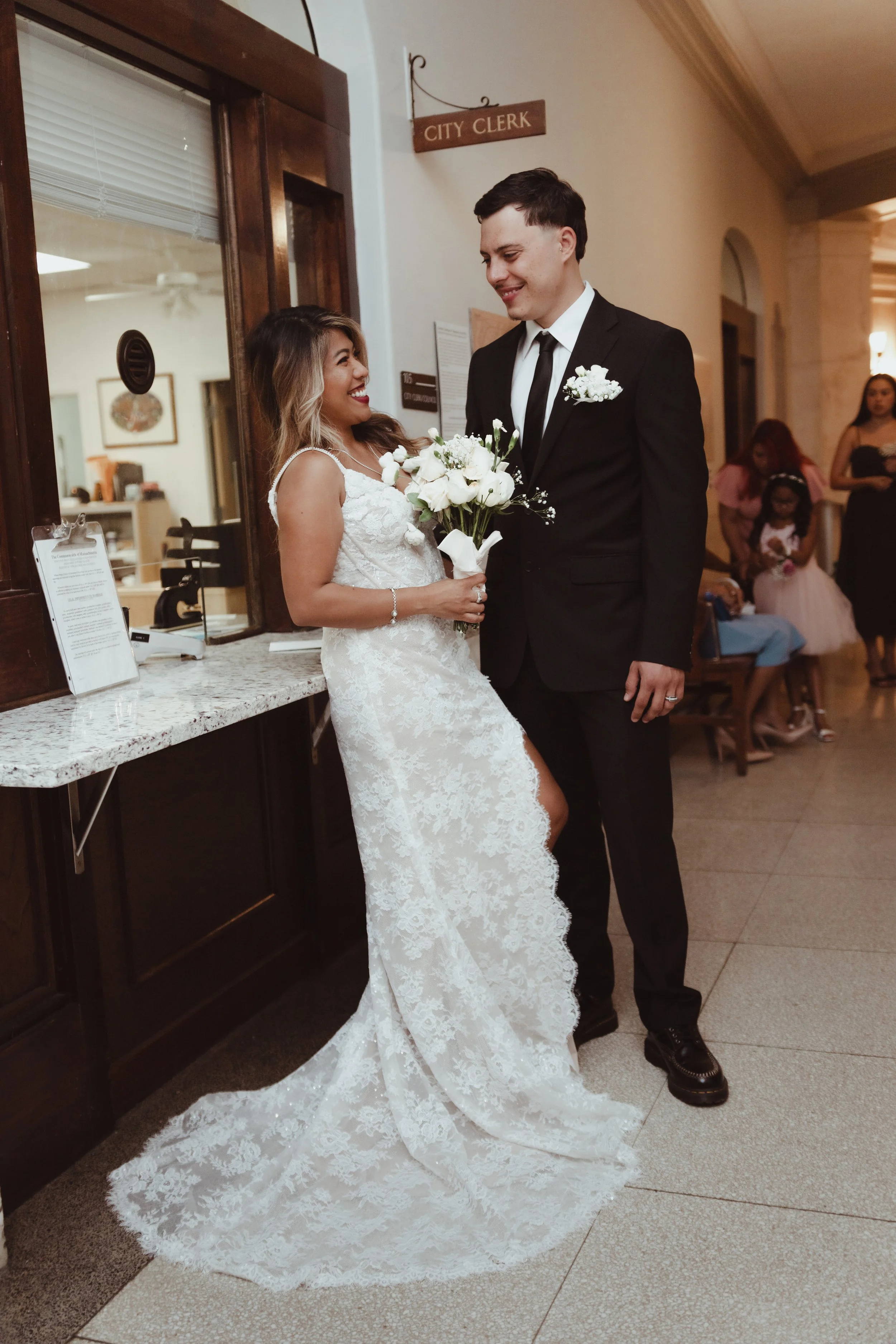 Newlywed couple posing with white bouquets in a city clerk's office