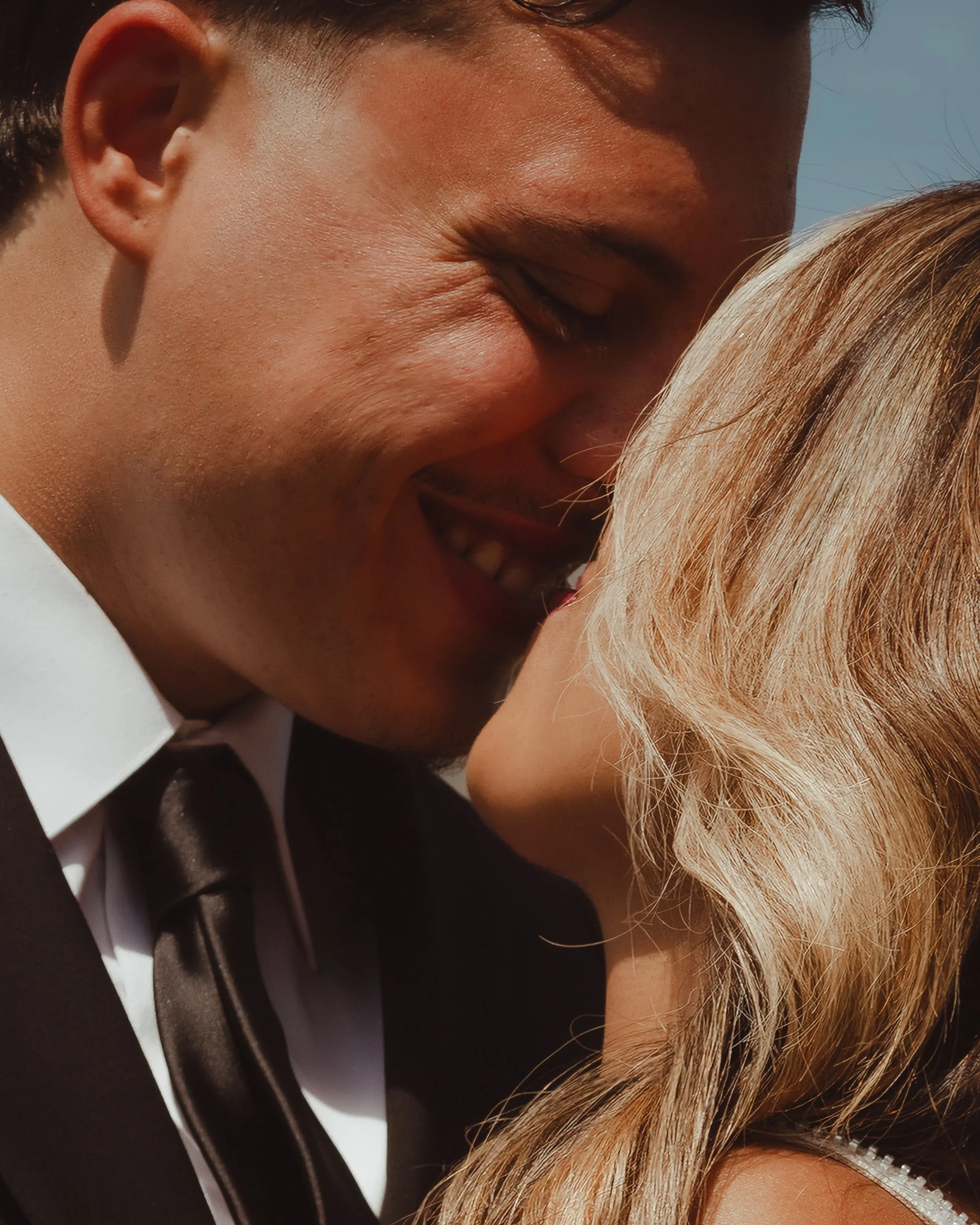 Close-up of a couple kissing outdoors in warm sunlight