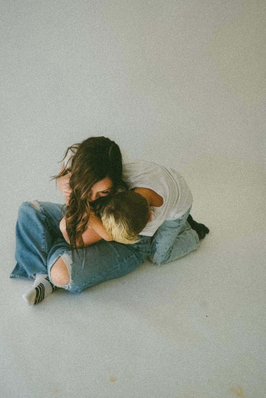 Young couple embracing while lying on a light-colored floor