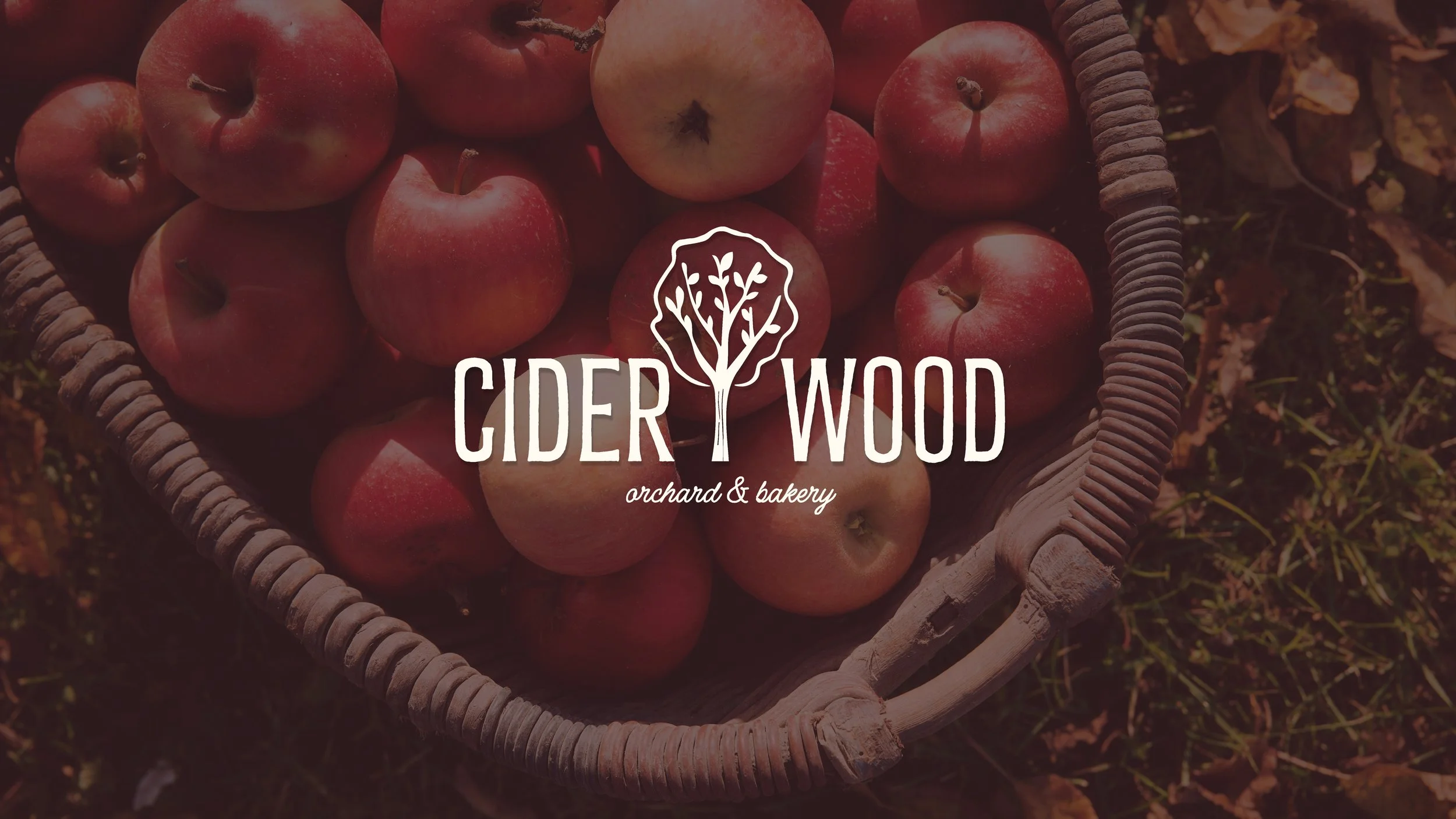 Basket of red apples with Cider Wood Orchard & Bakery logo