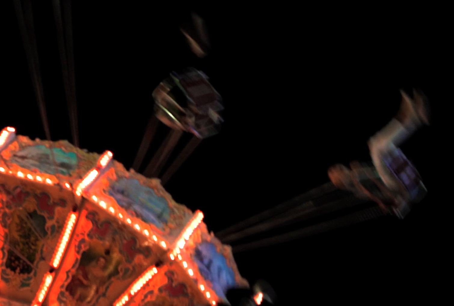 A lit carnival swing ride at night, still from Abandoned, a music video for A.S. Fanning