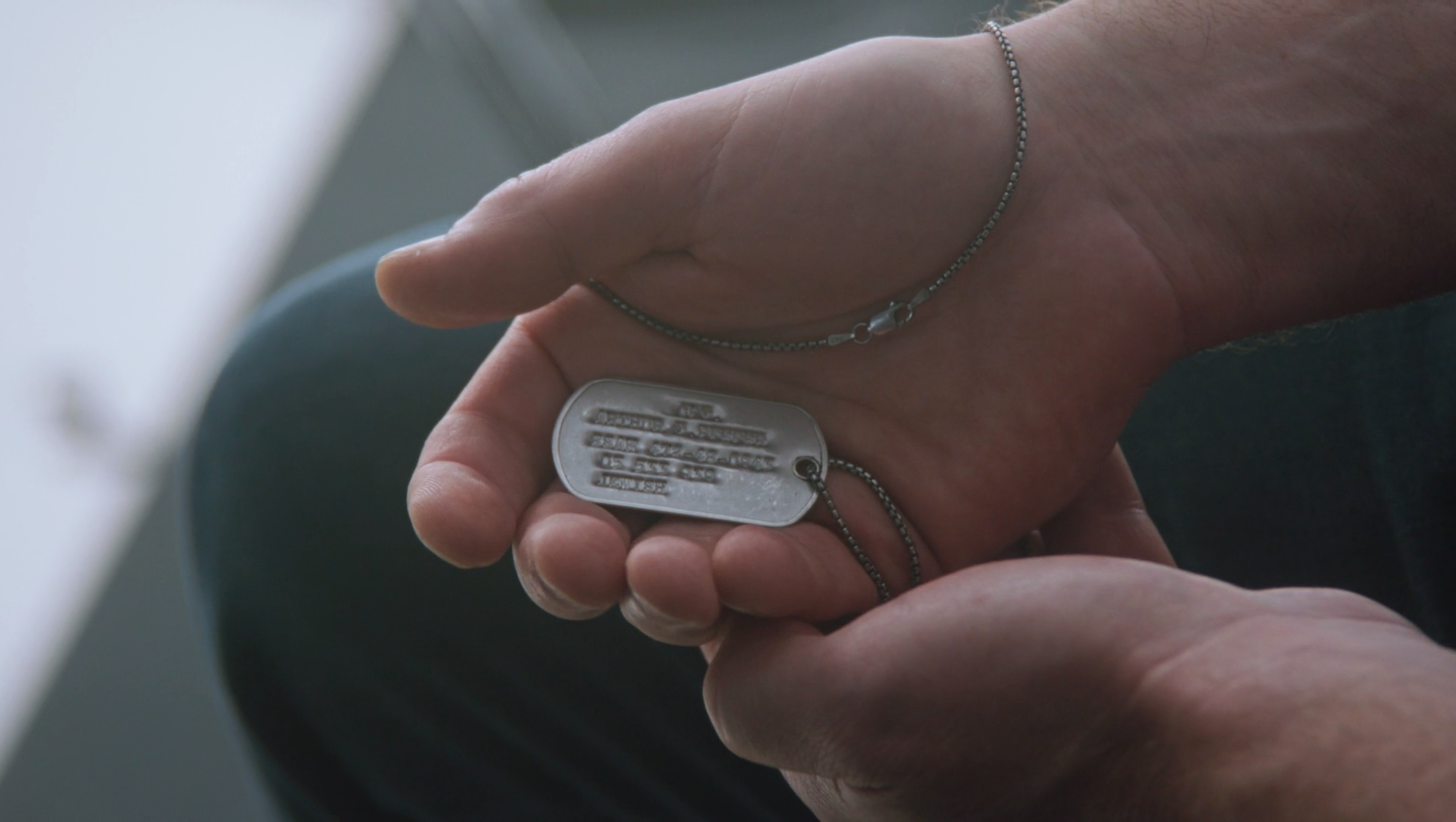 Hands holding a military dog tag, still from Courage, a campaign film for Dean Phillips for President