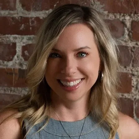 Portrait of Staci Wolff, CDRE, smiling against a brick wall
