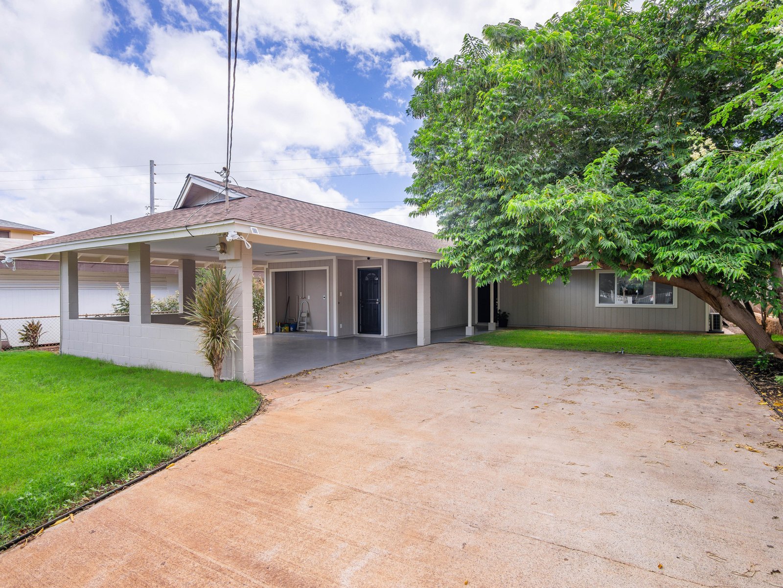 Single-story Oahu home with a wide driveway, green lawn, and a large tree
