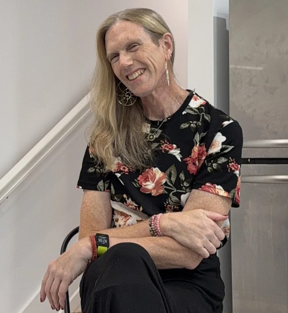 K. Davina Frick smiling, seated in a floral blouse.