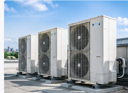 Unités extérieures de climatisation installées sur le toit d’un bâtiment, avec une ville en arrière-plan.