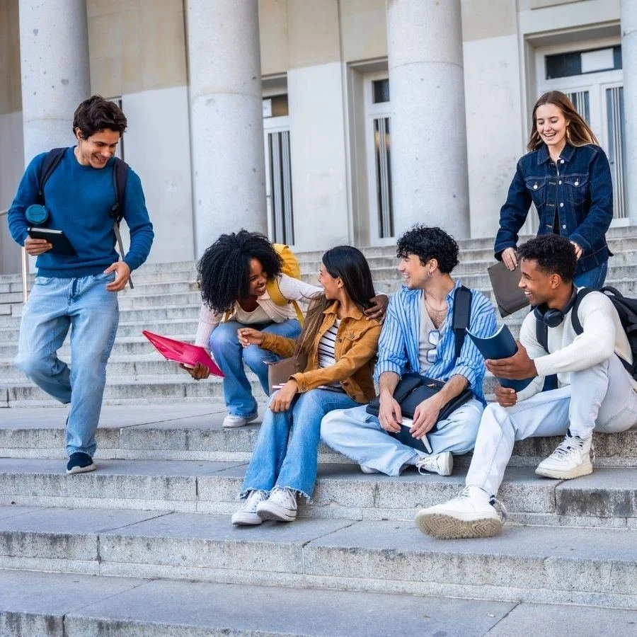 Diverse group of college students talking and laughing on campus steps