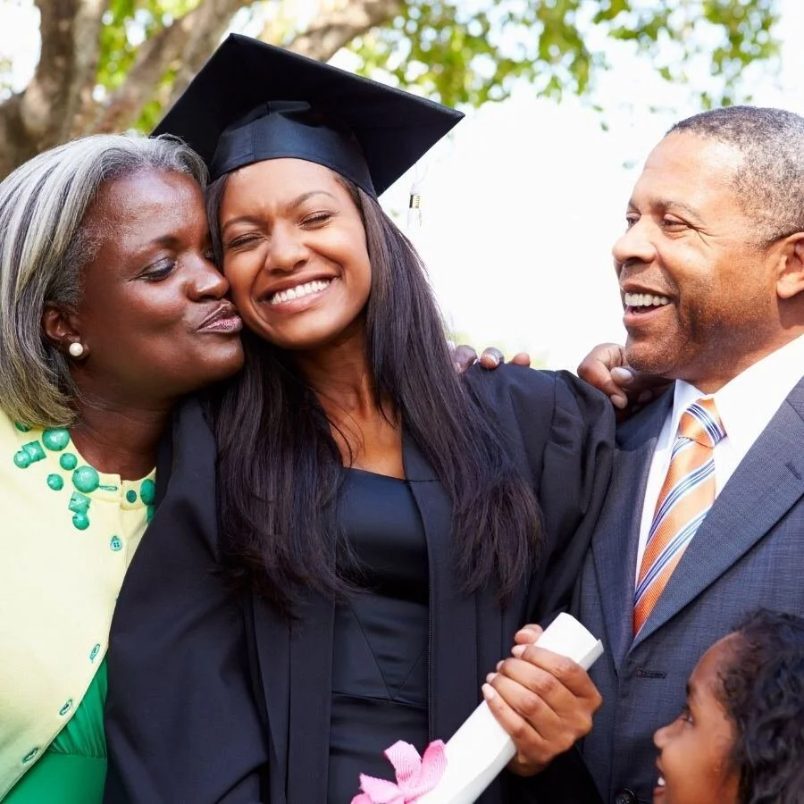 Smiling graduate in cap and gown celebrating with her family