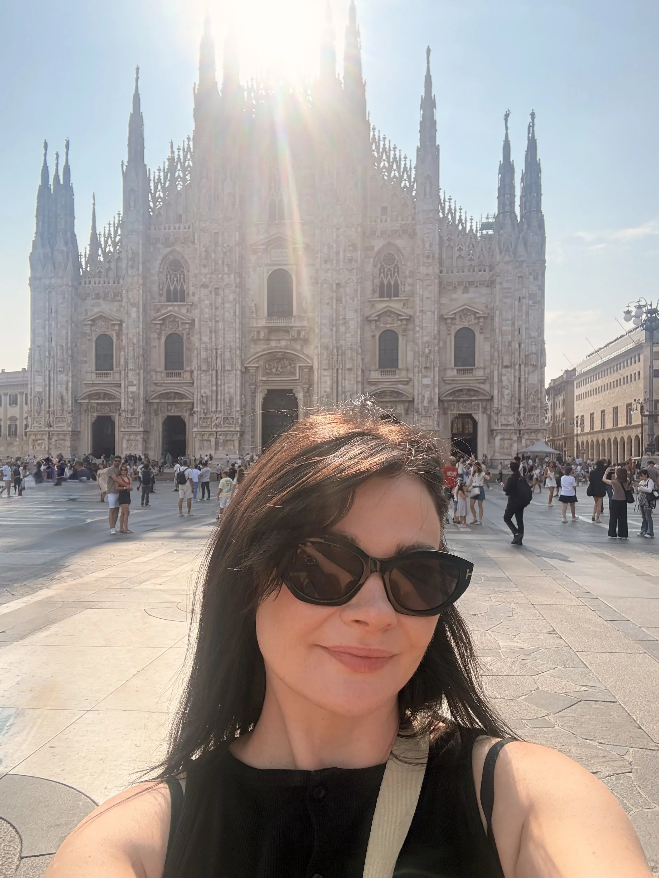 Woman wearing sunglasses takes a selfie in front of Milan Cathedral in Piazza del Duomo, Italy.