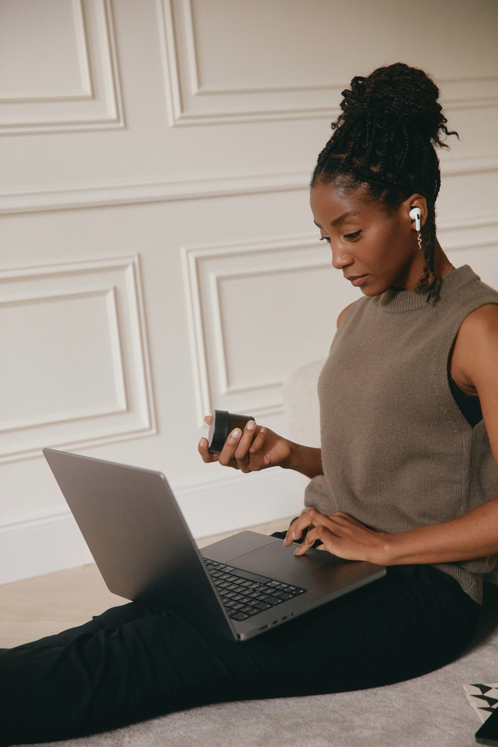 woman sitting on the floor works on her computer and phone