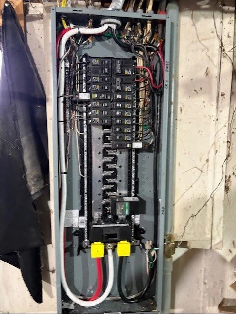 Open residential electrical breaker panel with circuit breakers, wiring, and main power cables