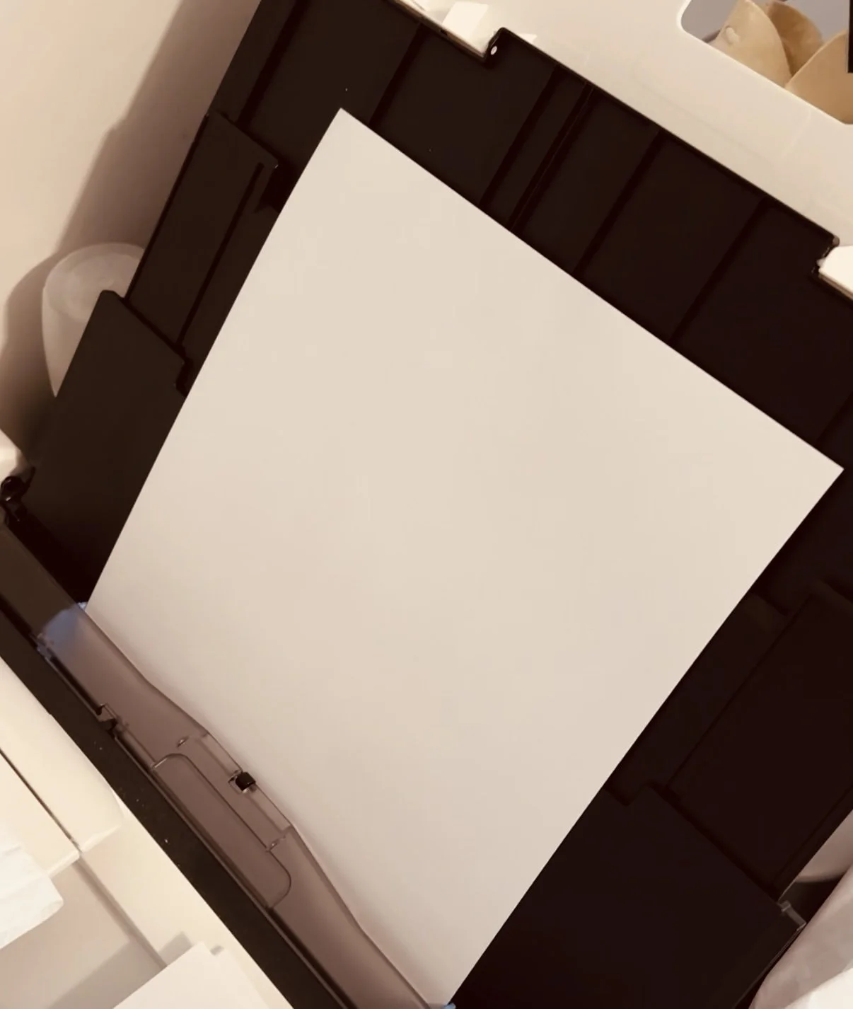 Blank white sheet of paper inside an open black printer or copier paper tray