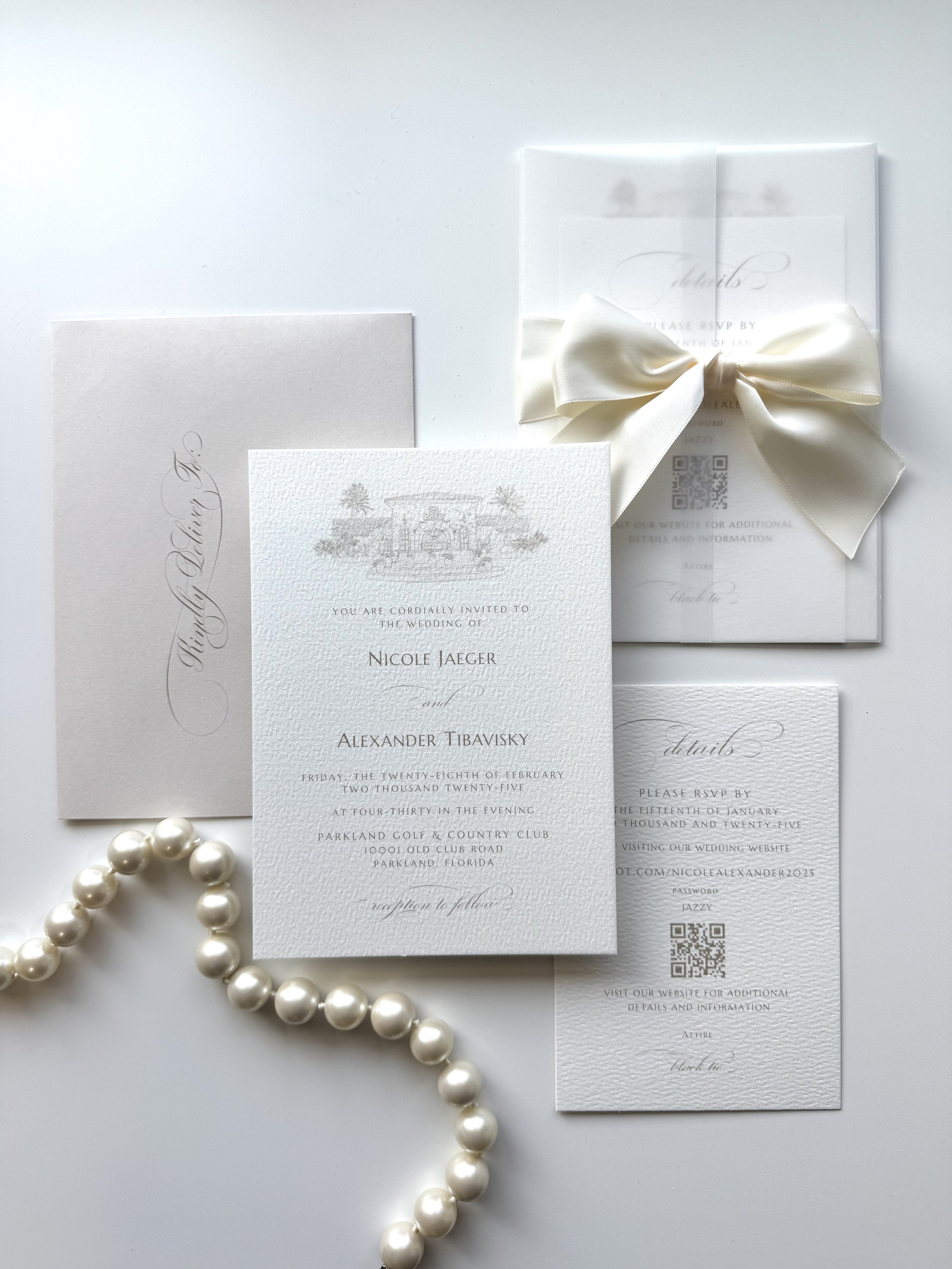 Elegant flat-lay of white wedding invitation suite, featuring a satin bow, pearl strand, RSVP card, custom venue sketch, and beige envelope.