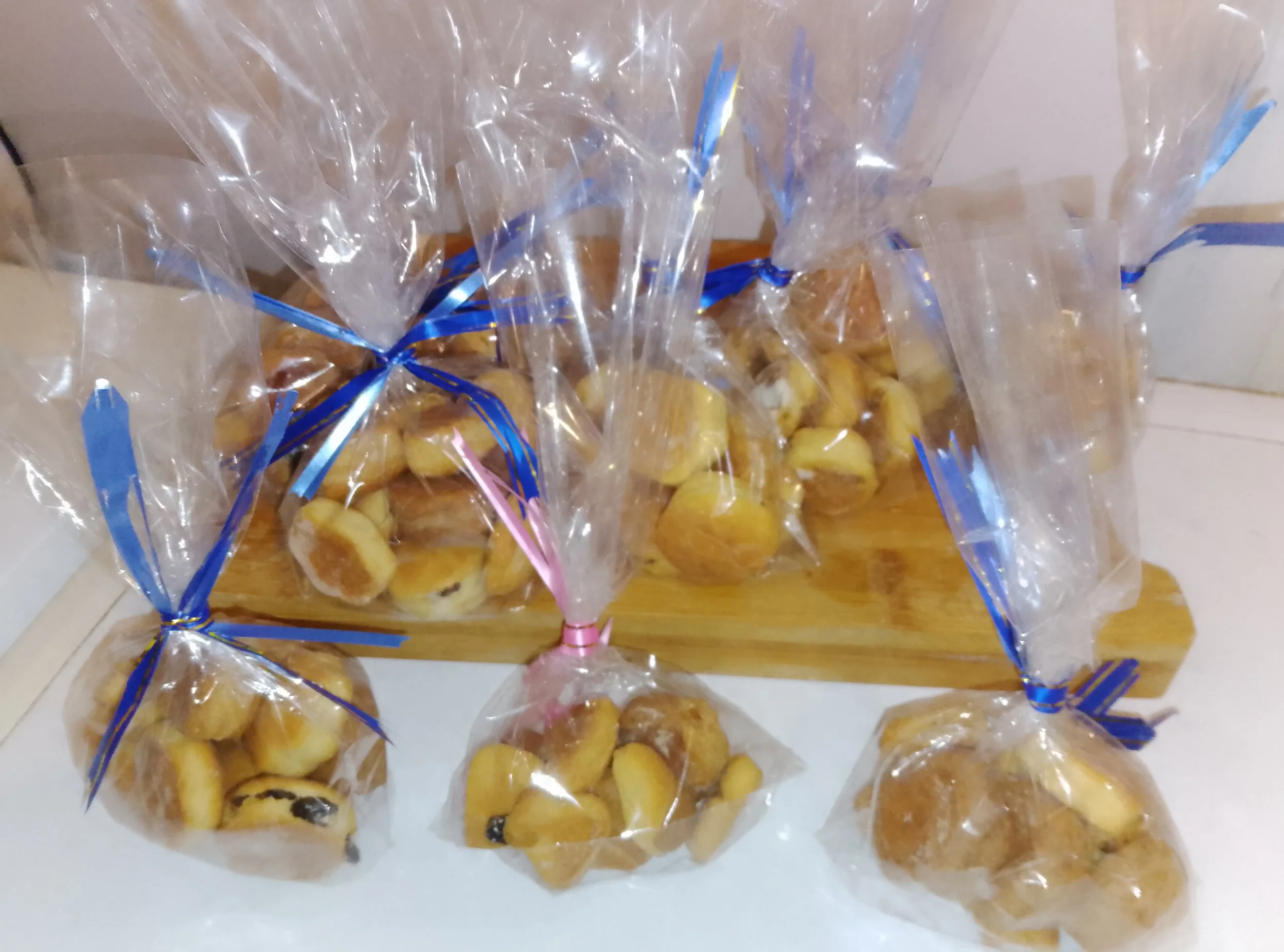 Sachets transparents de petits pains et viennoiseries attachés avec des rubans bleus et roses.