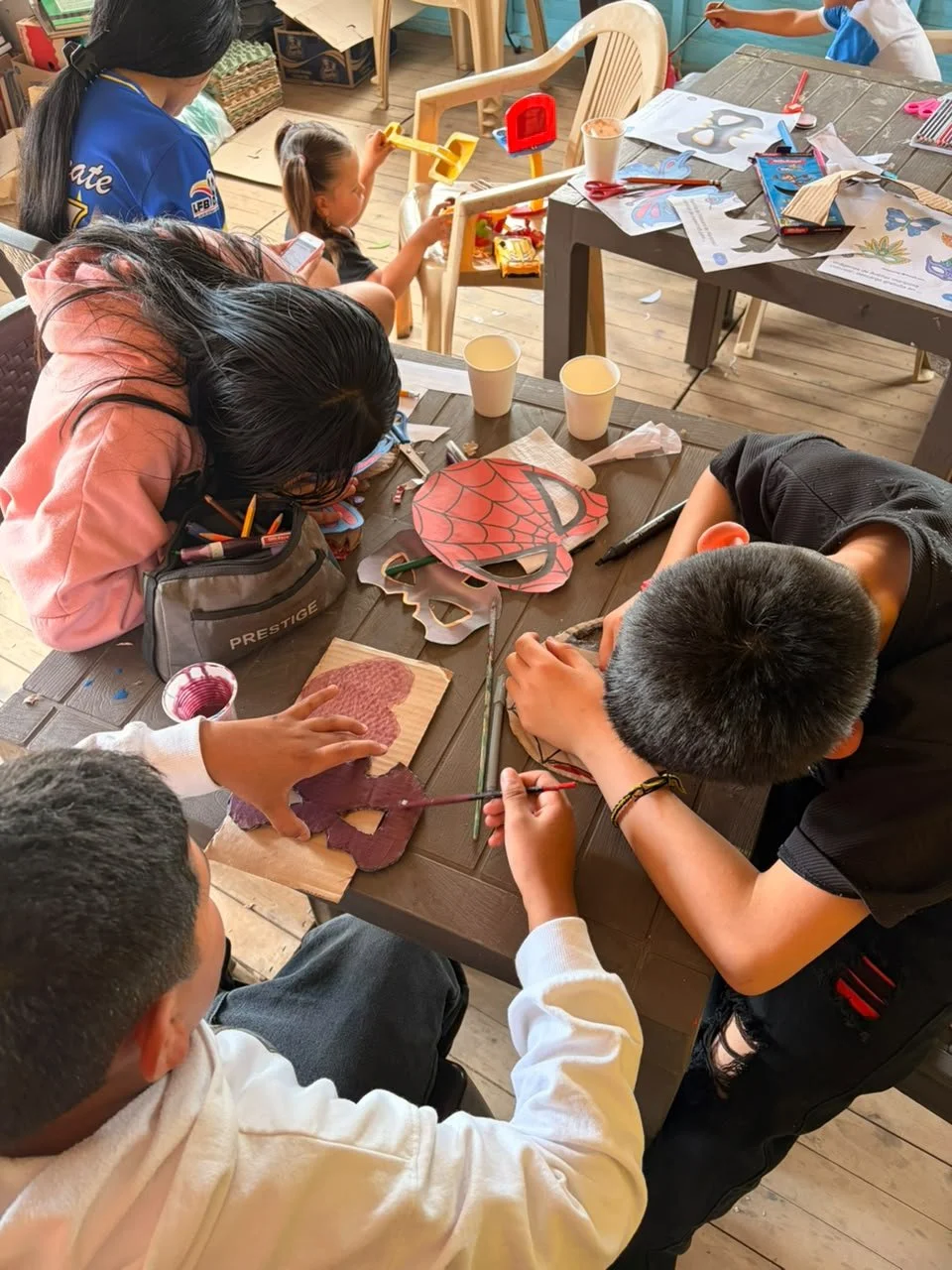 Niños y adolescentes realizan manualidades y colorean máscaras de superhéroes en la celebración del día de la niñez.