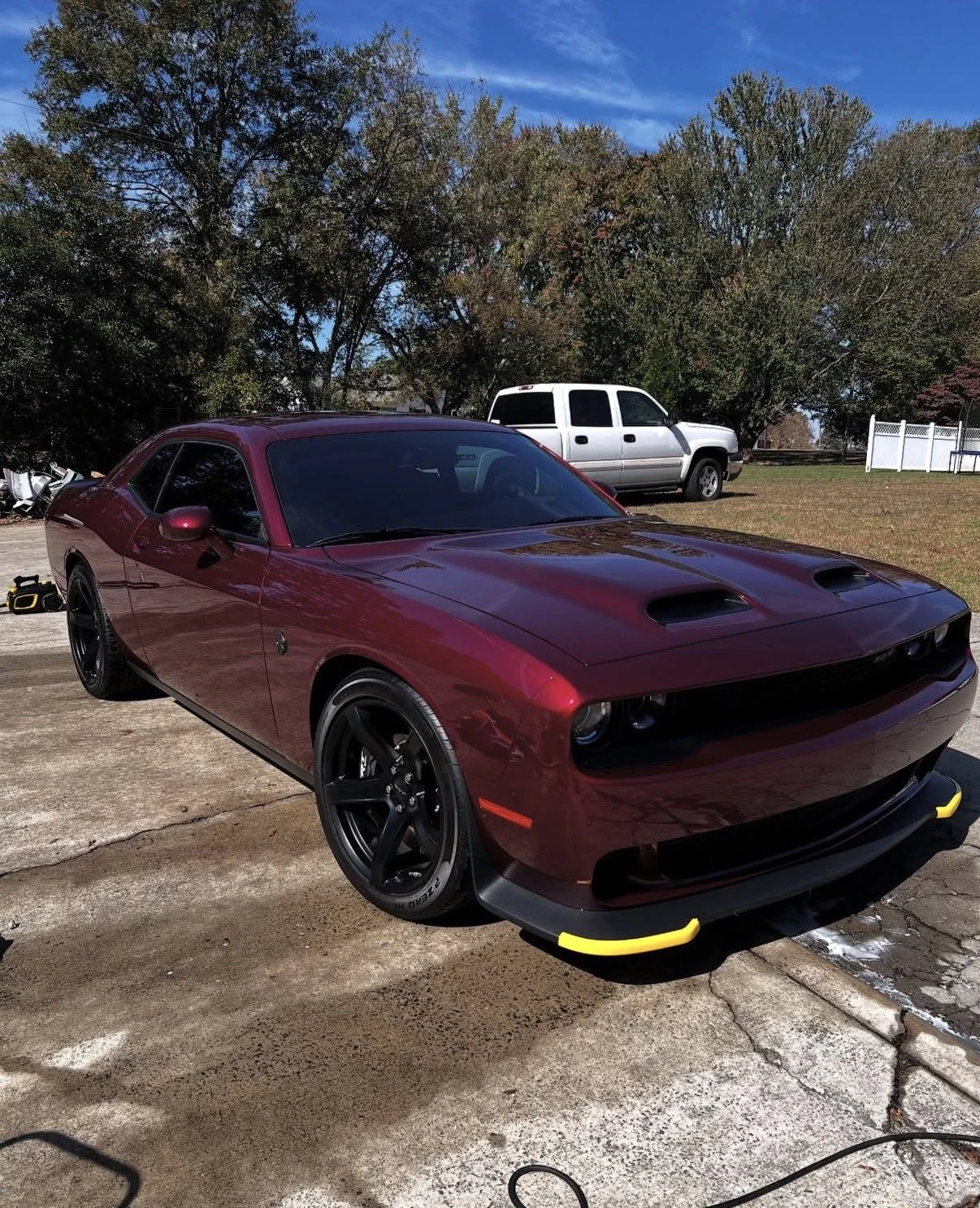 Burgundy Dodge Challenger with black wheels and yellow bumper guards parked in a driveway.