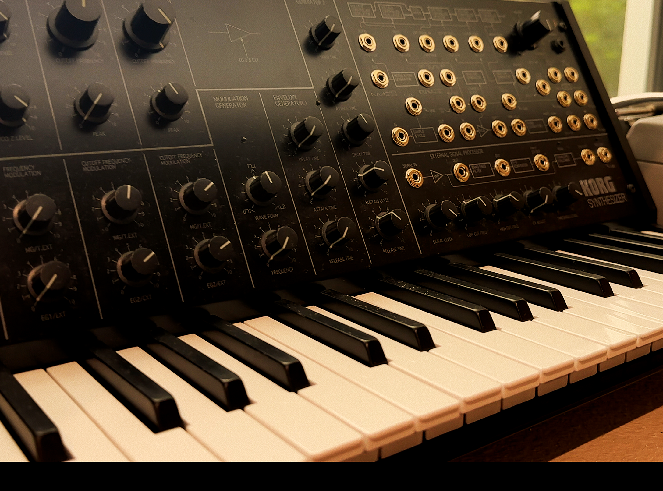 Close-up of a Moog synthesizer control panel with knobs, patch connections, and piano keys.