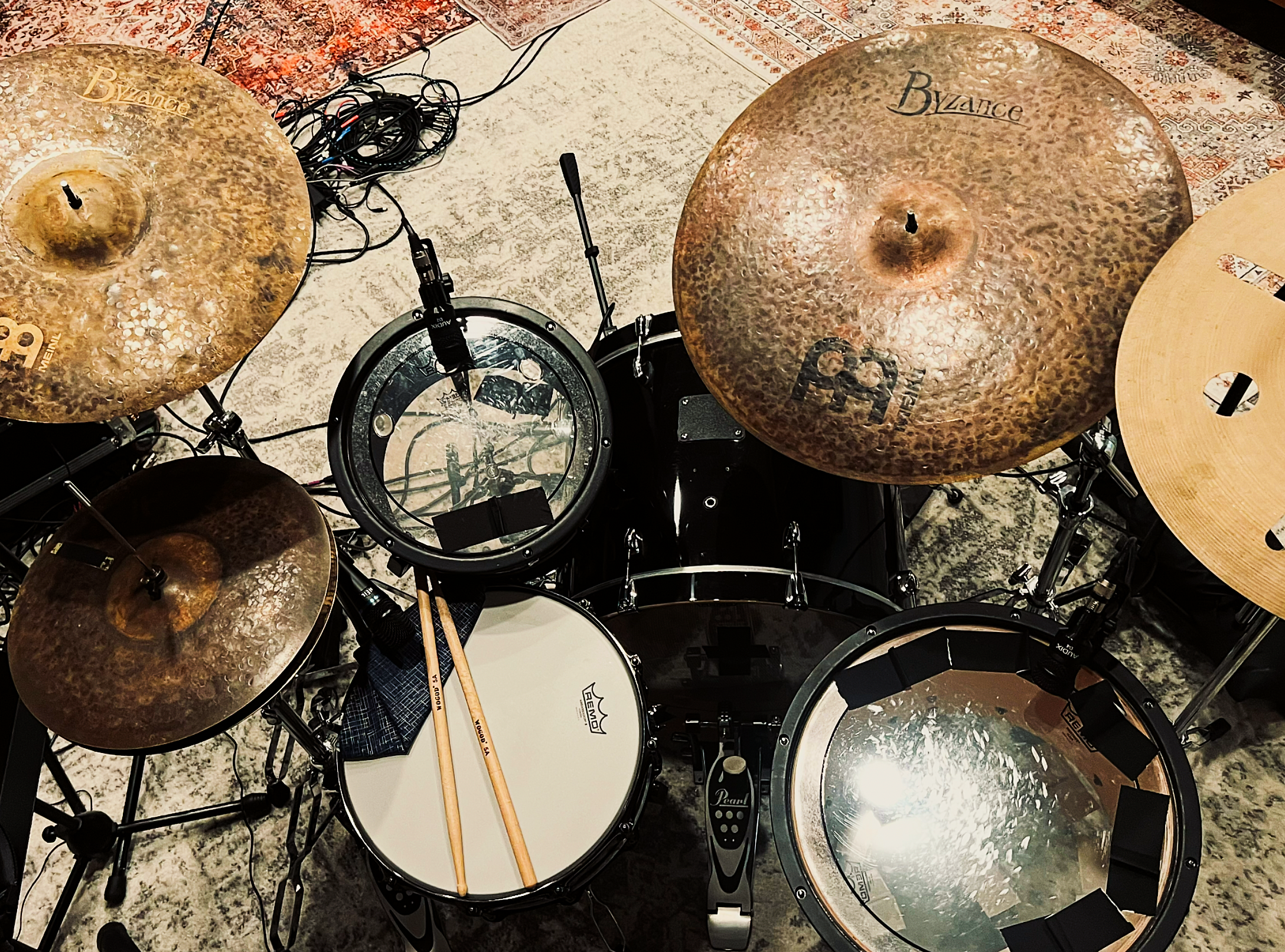 Overhead view of an electronic drum kit with cymbals, drum pads, microphones, cables, and drumsticks.