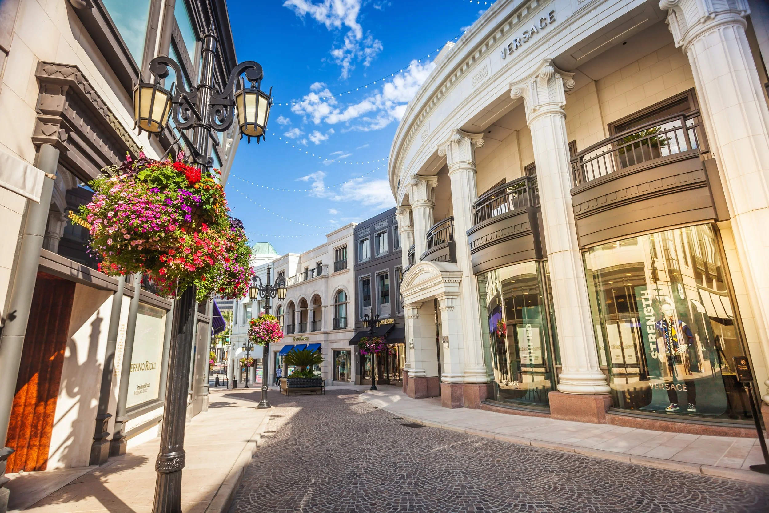 Rodeo Drive shopping street in Beverly Hills with luxury storefronts, flower baskets and string lights